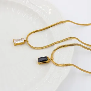 Macro detail of rectangle cut white and black zircon pendants on gold snake chains
