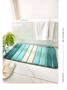 Vue détaillée du tapis de bain rayé bleu sarcelle sur sol en marbre près de la baignoire