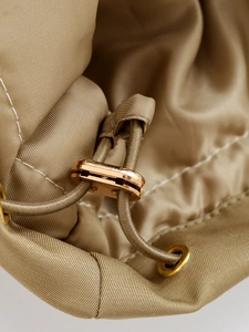 Detail of khaki jacket with metallic gold drawstring toggles and high-density fabric
