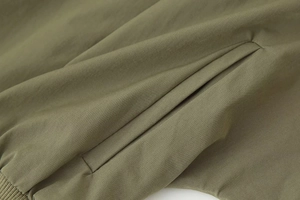 Détail de la poche latérale de veste vert militaire avec tissu tissé et bord côtelé