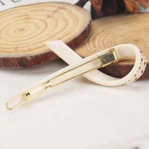 Detailansicht der cremefarbenen Acetat-Haarspange mit Champagner-Steinen und goldener Metallspange
