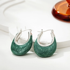 Detail of U-shaped silver hoop earrings with green marbled enamel texture on white stand