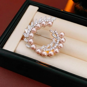 Elegant gold-plated round brooch with pink pearls and cubic zirconia on jewelry box