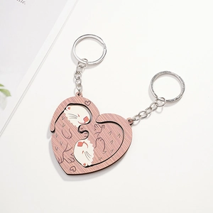 Close-up of wooden otter couple keychains forming a heart shape on a white desk