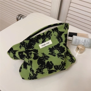 Detail of green floral canvas makeup bag with Simple Wish label on a vanity desk