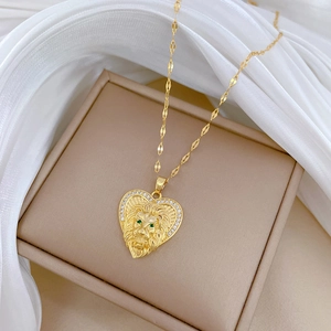 Detailed close-up of gold lion heart pendant with green stones on white silk