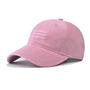 Close-up of pink cotton baseball cap featuring white embroidered letters and twill fabric