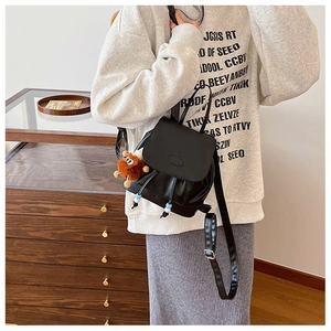 Detail of black matte PU mini backpack with drawstring closure and brown bear charm accessory