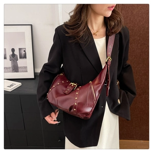 Detail view of burgundy leather hobo bag with gold rivets and adjustable shoulder strap