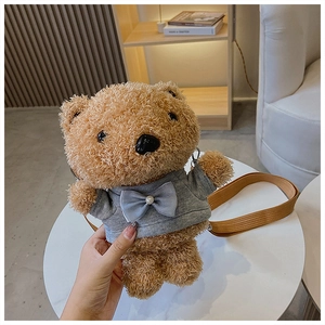 Close-up of cute light brown plush bear bag with grey outfit and blue bow detail