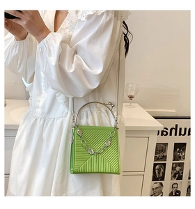 Detail of bright green square handbag featuring geometric embossing and silver ring handle