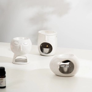 Detailed view of three spotted ceramic essential oil burners in minimalist human face style