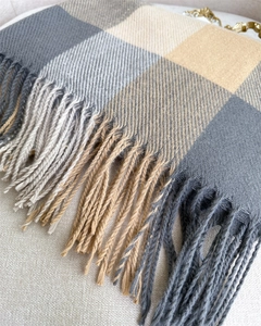 Close-up detail of soft plaid scarf fabric with gray and beige tassels