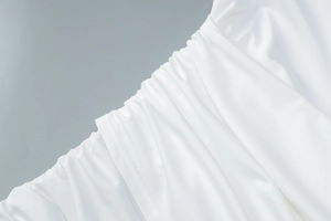 Close-up of white dress with elegant ruched waist detailing and smooth fabric texture