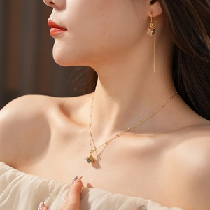 Detail view of gold-plated opal cube necklace and earrings worn by model in soft light