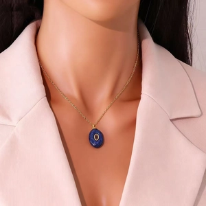 Detailed view of a gold chain necklace featuring an oval blue pendant with letter O