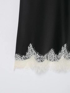 Vue détaillée du tissu en satin noir avec des finitions en dentelle florale blanche élégante