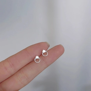 Detail shot of tiny silver star earrings on finger to show minimalist scale and texture