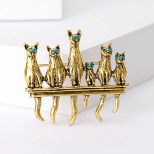 Vintage gold alloy brooch featuring six cats with green rhinestone eyes on a bar