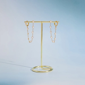 Detail of gold-plated tassel earrings with dangling round cubic zirconia chains