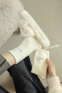 Detail of plush off-white winter socks featuring a cute blue rabbit embroidery pattern