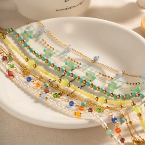 Close-up of colorful bohemian bead anklets with shell charms on a white ceramic plate