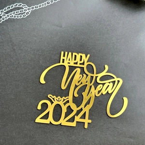 Golden acrylic Happy New Year 2024 cake topper on a dark textured background