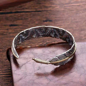 Macro shot of silver and gold feather cuff bracelet with detailed texture on leather