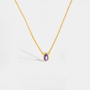 Macro shot of polished purple pear-cut gemstone pendant on elegant gold chain