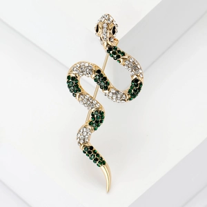 Macro detail of gold snake brooch with sparkling rhinestones and green gem eyes