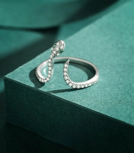 Close-up of snake-shaped silver ring with green gem eyes and pavé-set stones