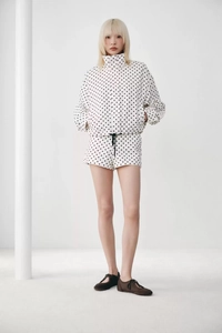Detailansicht der weißen Damenjacke mit Punkten, Stehkragen und Kordelzug an den Shorts