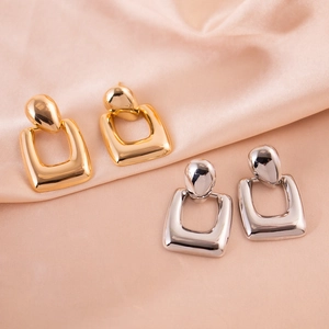 Detailed view of gold and silver hollow geometric rectangular drop earrings on silk