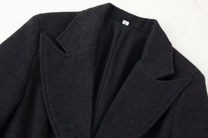 Detail view of the notch lapel and charcoal grey wool texture on this long coat