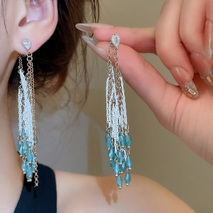 Détail de boucles d'oreilles pendantes en cristal bleu avec pampilles sur un mannequin