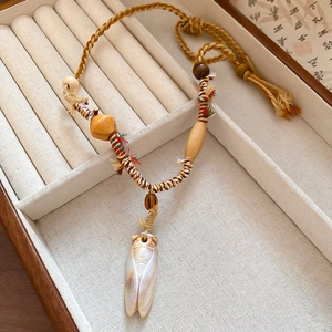 Detail of hand-carved cicada pendant in translucent resin on a braided brown cord