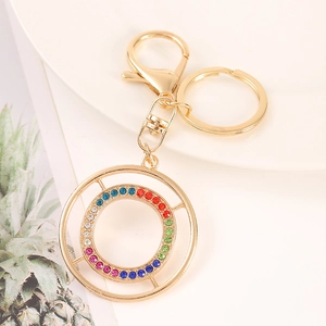Detail of a golden alloy alphabet keychain featuring colorful rhinestones on a round pendant