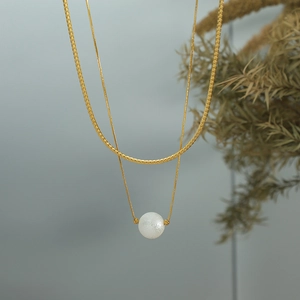 Elegant double-layered gold snake chain necklace featuring a textured white pearl pendant