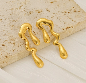 Close-up of golden irregular fluid geometric earrings with mirror polished finish