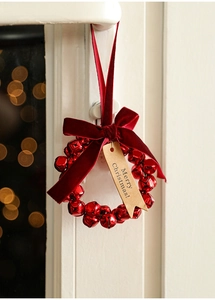Detail of red metal bell wreath with velvet bow and Merry Christmas tag on a door