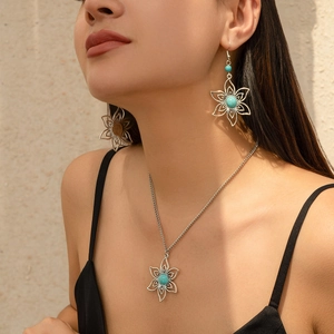 Detail of vintage silver hollow flower necklace and turquoise earrings on model