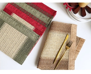 Close-up detail of woven paper rope placemats with red and green festive striped texture