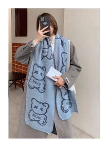 Detail of light blue knitted scarf with dark line-drawn bear patterns and BEAR text