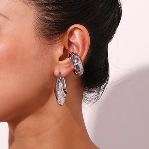 Close-up of silver heart pattern ear cuff and dangle earring set on a female model
