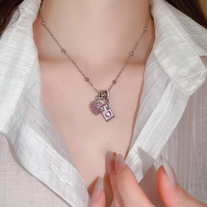 Detail of silver necklace with pink heart and square charms on a female model