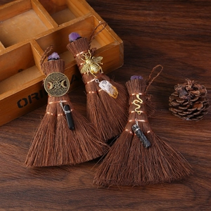 Mini Wicca palm brooms with natural crystals and witchy charms on dark wood