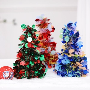 Close-up of red, green, and blue sequin Christmas trees on a white snowy surface