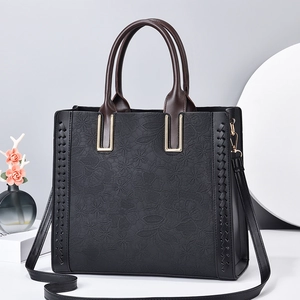 Elegant black tote bag with embossed floral texture and contrast brown handles for women