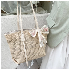 Close-up of woven straw tote bag featuring delicate lace bow and pink rose embroidery