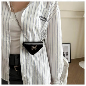 Détail d'un mini sac triangle en cuir brillant avec breloque papillon argentée